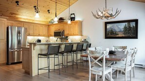 Une cuisine dotée de meubles en bois, d’appareils électroménagers en acier inoxydable et d’un coin repas avec une table et des chaises en bois.