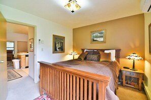A bedroom with a wooden headboard, a bed with pillows, a nightstand with a lamp, and a framed picture on the wall. - Private deck, BBQ Grill, view of golf course (Eden)