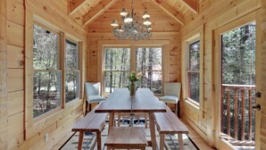 A wooden cabin with a large dining table, benches, and a chandelier.