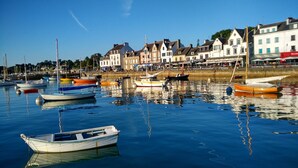 Ein Yachthafen mit verschiedenen Schiffen, eine Uferpromenade mit Gebäuden und ein klarer Himmel.