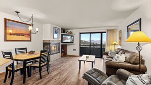 Una sala de estar con una mesa de comedor de madera, sillas, un sofá y un televisor.