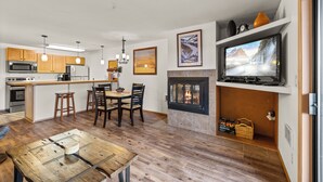 Una cocina moderna con armarios de madera, una isla central y una zona de comedor con mesa y sillas de madera.