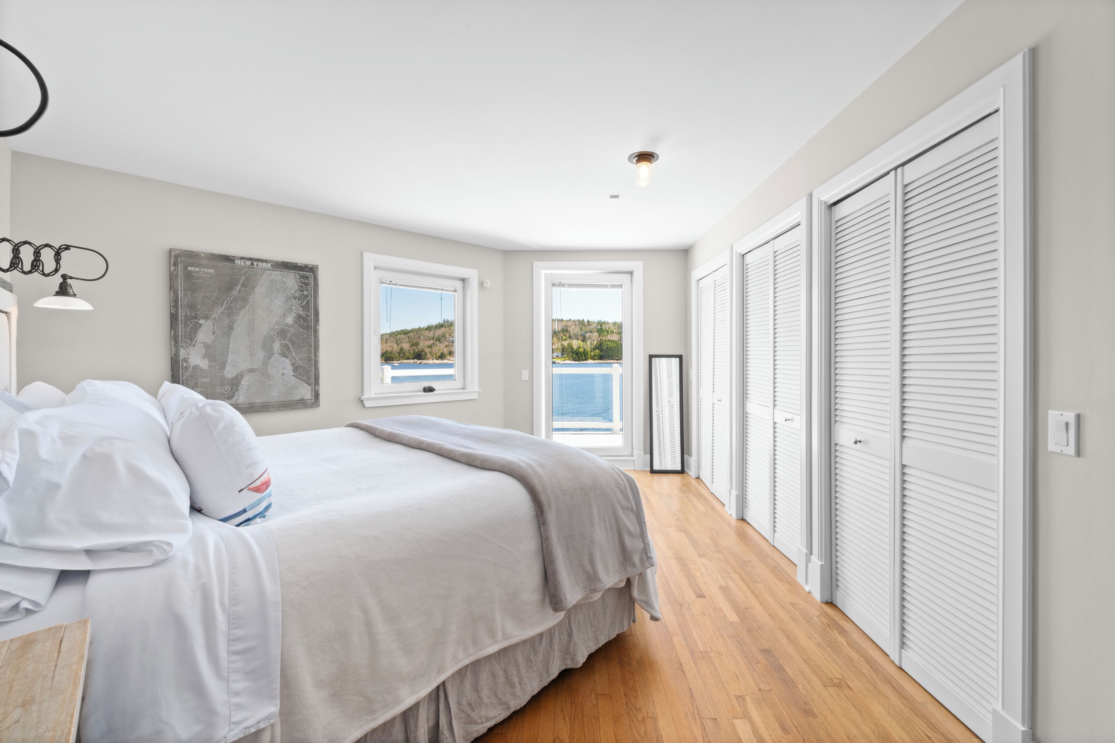 A bedroom with a bed, a map on the wall, and a view of the outdoors.