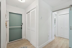 A hallway with white walls, a wooden floor, and a door with a frosted glass panel.