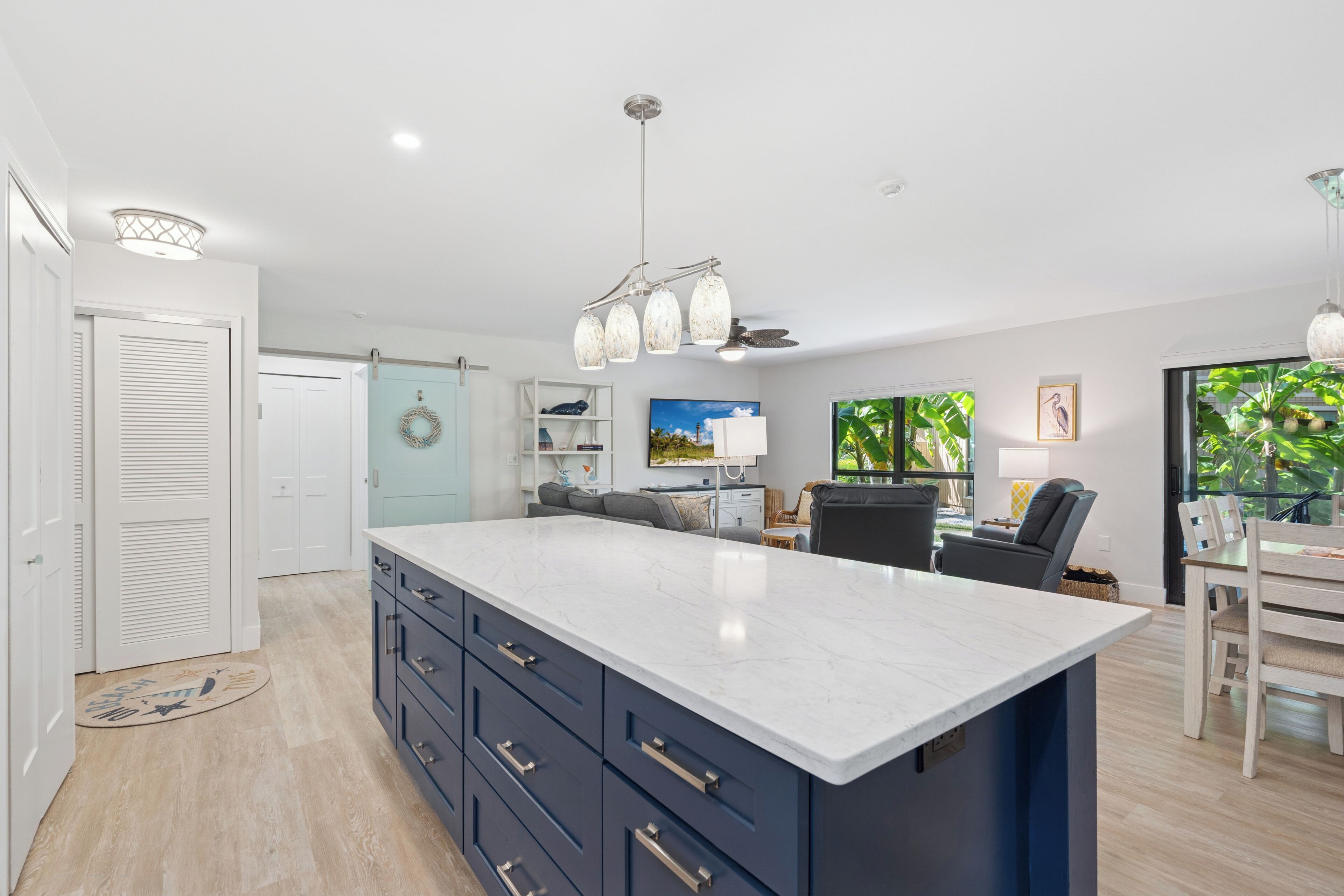 A modern kitchen with a large island, built-in appliances, and a dining area with a view of greenery.