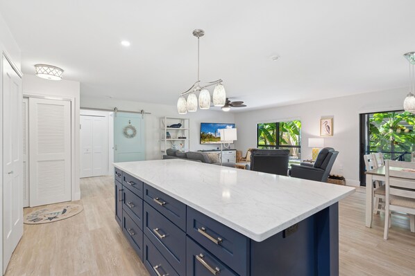 A modern kitchen with a large island, built-in appliances, and a dining area with a view of greenery.