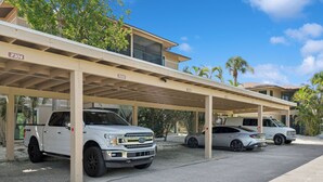 A covered parking area with three vehicles parked under a structure.