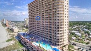A high-rise hotel with multiple balconies, a rooftop pool, and a view of the surrounding area.