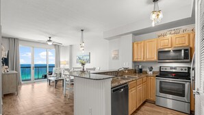 A modern kitchen with wooden cabinets, stainless steel appliances, and a view of the ocean.