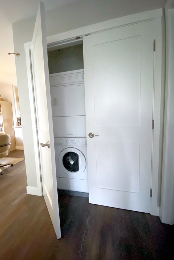 Un cuarto de lavandería con lavadora, secadora y una puerta blanca.