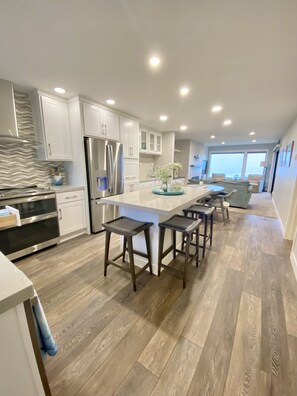 Una cocina moderna con armarios blancos, electrodomésticos de acero inoxidable y suelo de madera.