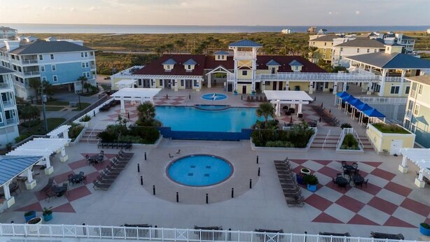 A resort with a central pool, outdoor seating, and a view of the ocean.
