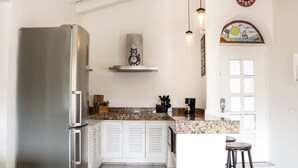 A modern kitchen with a stainless steel refrigerator, white cabinetry, a granite countertop, and a hanging light fixture. - Marina Golf Condo in the heart of the Marina Vallarta (Marina Vallarta)