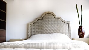 A bedroom with a tufted headboard, a patterned wall, and a decorative vase with bamboo sticks. - Marina Golf Condo in the heart of the Marina Vallarta (Marina Vallarta)