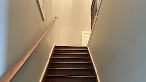A wooden staircase with a handrail on the left and a door at the top. - King's Country Suite (Narvon)