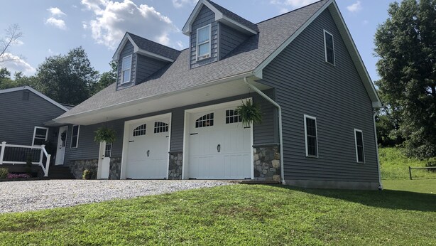 A two-story house with a garage, a covered porch, and a stone foundation. - King's Country Suite (Narvon)