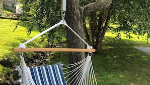 A blue and white striped hammock chair suspended from a tree. - King's Country Suite (Narvon)
