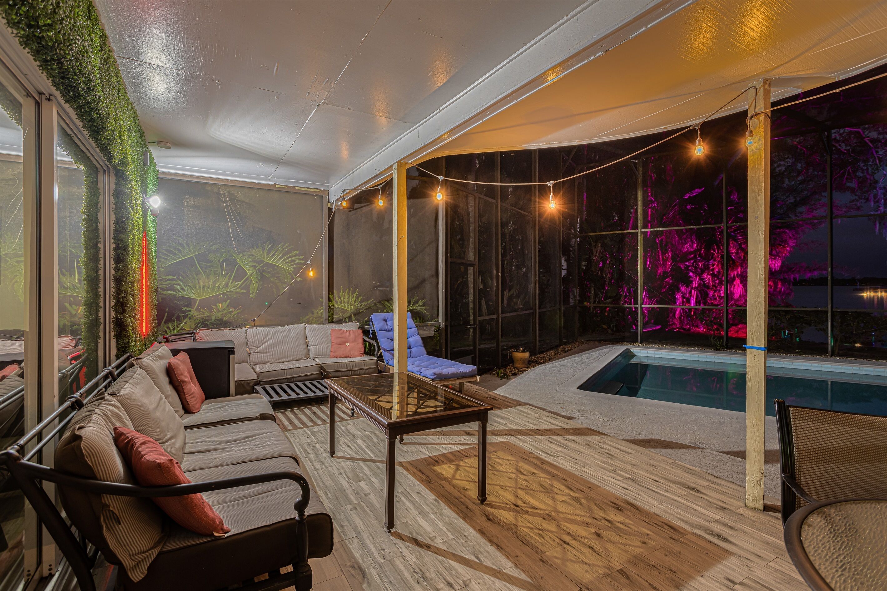 An outdoor seating area with a pool, covered by a transparent roof, and surrounded by glass walls.
