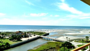 Une vue côtière comprenant une jetée, une plage et un pont menant à une péninsule.