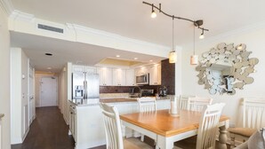 Une cuisine moderne avec des meubles blancs, un îlot central et des luminaires suspendus.