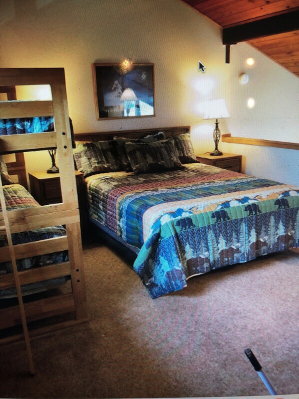 A bedroom with a bunk bed, a flat-screen TV mounted on the wall, and a bedside table with a lamp. - Pet friendly, newly updated, 2 bedroom and a loft woodlands unit (Mammoth Lakes)