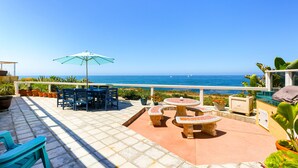 Une terrasse aménagée avec du mobilier d’extérieur, une table et un parasol, offrant une vue sur la côte.