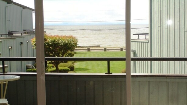 Un balcón con vista al mar, una mesita y una silla.