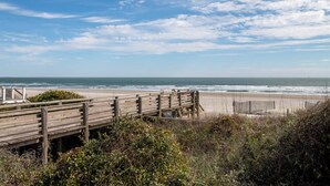 Une jetée en bois menant à une plage avec vue sur l’océan.