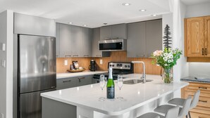 Una cucina moderna con elettrodomestici in acciaio inossidabile, un'isola centrale con sgabelli da bar e un vaso decorativo con fiori.