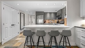 Una cucina moderna con isola centrale, sgabelli da bar e diversi mobili.