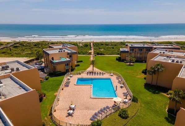 Una piscina en la azotea con vistas a la playa, rodeada de edificios.