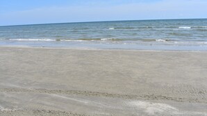 A beach with a sandy shore and calm waves. - Don't Cross Seawall to Get to the Beach!!! (Galveston)
