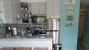 Una cocina moderna con gabinetes grises, un refrigerador de acero inoxidable y una isla central con taburetes.