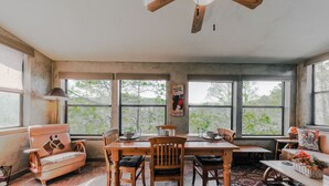 Un comedor rústico con mesa y sillas de madera, un banco y un ventilador de techo.