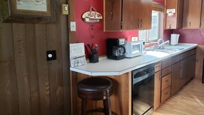 Une cuisine avec des meubles de rangement en bois, une machine à café, un four à micro-ondes et un évier.