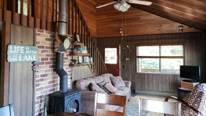 Un intérieur de chalet chaleureux avec une cheminée, des murs en bois, un canapé et un téléviseur.