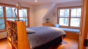 A bedroom with a bed, a desk, a chair, a bookshelf, and large windows. -  New Well Built Elegant Home on the Water 2 miles to Freeport, 9  to Portland! (South Freeeport)