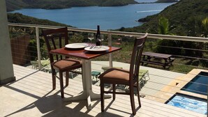 A terrace with a table and chairs overlooking a scenic view of a lake and mountains.