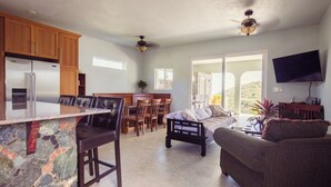 A spacious kitchen with a stone countertop, wooden cabinets, and a dining area with a table and chairs.