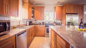 A modern kitchen with wooden cabinets, stainless steel appliances, and a granite countertop.
