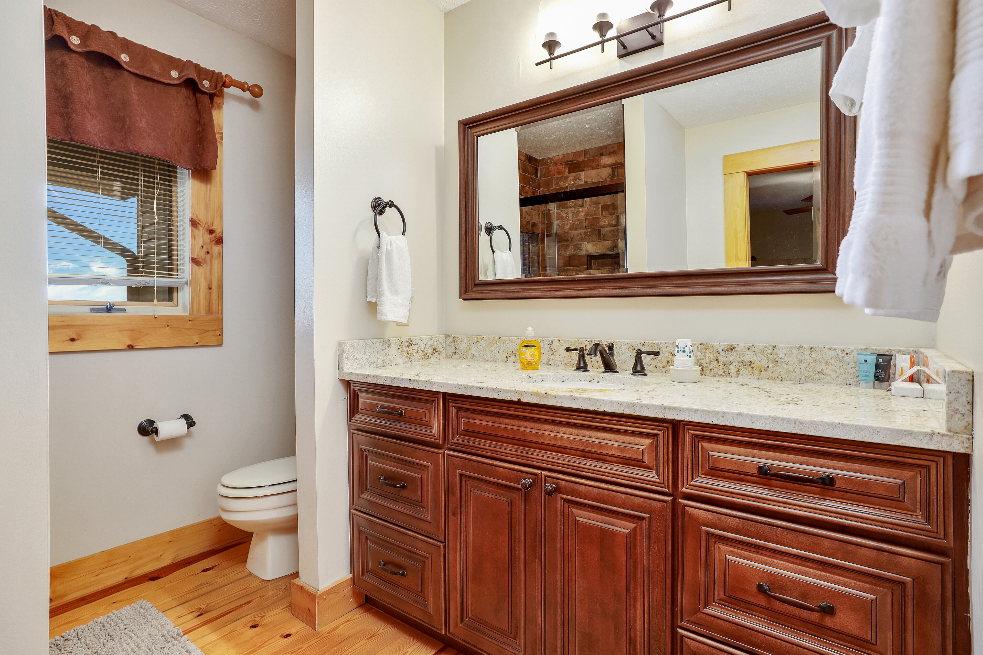 Un baño con armarios de madera, un espejo grande y un inodoro.