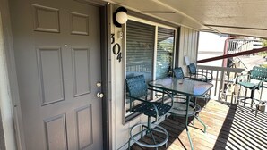 Eine überdachte Terrasse mit Tisch und Stühlen, eine Tür mit Briefkasten und Blick auf den Garten.