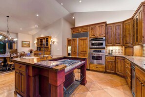 Una cocina amplia con armarios de madera, una isla central con estufa integrada y electrodomésticos de acero inoxidable.