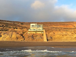 Ein zweistöckiges Gebäude mit einem Balkon mit Blick auf Strand und Meer.