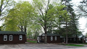 A row of log cabins with a paved driveway in front. - 3-Bed Sleeping Cabin Near Geneva Lake – Walk to Dining & Beach (Williams Bay)