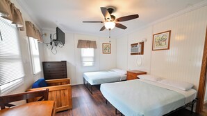 A room with two single beds, a wooden table, a chair, a ceiling fan, and a TV mounted on the wall. - 3-Bed Sleeping Cabin Near Geneva Lake – Walk to Dining & Beach (Williams Bay)