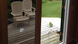 A sliding glass door leading to an outdoor deck with two white chairs.