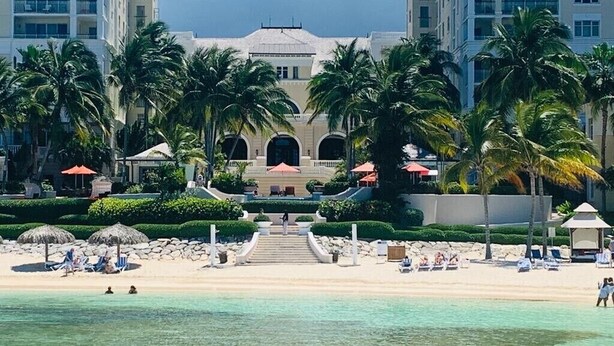 A beachfront hotel with a central building, palm trees, and a sandy beach. - "Sought-After" Luxurious 2100 sq ft Oceanfront Private Residence, in a Resort (Montego Bay)