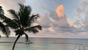 A beach with palm trees, thatched umbrellas, and lounge chairs. - "Sought-After" Luxurious 2100 sq ft Oceanfront Private Residence, in a Resort (Montego Bay)