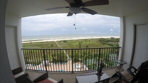 A balcony with a view of the beach, outdoor furniture, and a ceiling fan. - Paradise on the beach in an oceanfront, luxury condo on Sand Key (Clearwater Beach)